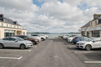 Vue large d'un parking d'agences de location de voitures en Loire-Atlantique avec plusieurs véhicules alignés sous un ciel nuageux typique de la région