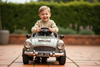 Enfant souriant conduisant une mini voiture électrique style classique britannique dans un jardin